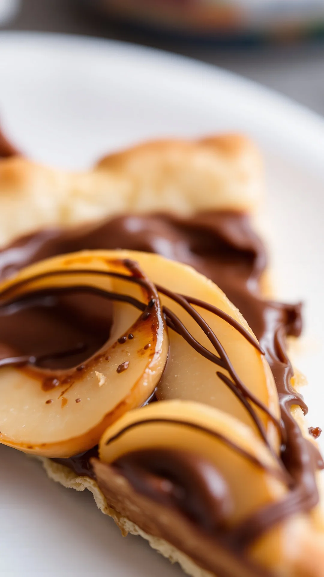 Close-up macro shot of a slice of pear and Nutella tart showing creamy chocolate hazelnut filling, caramelized pear slices, f