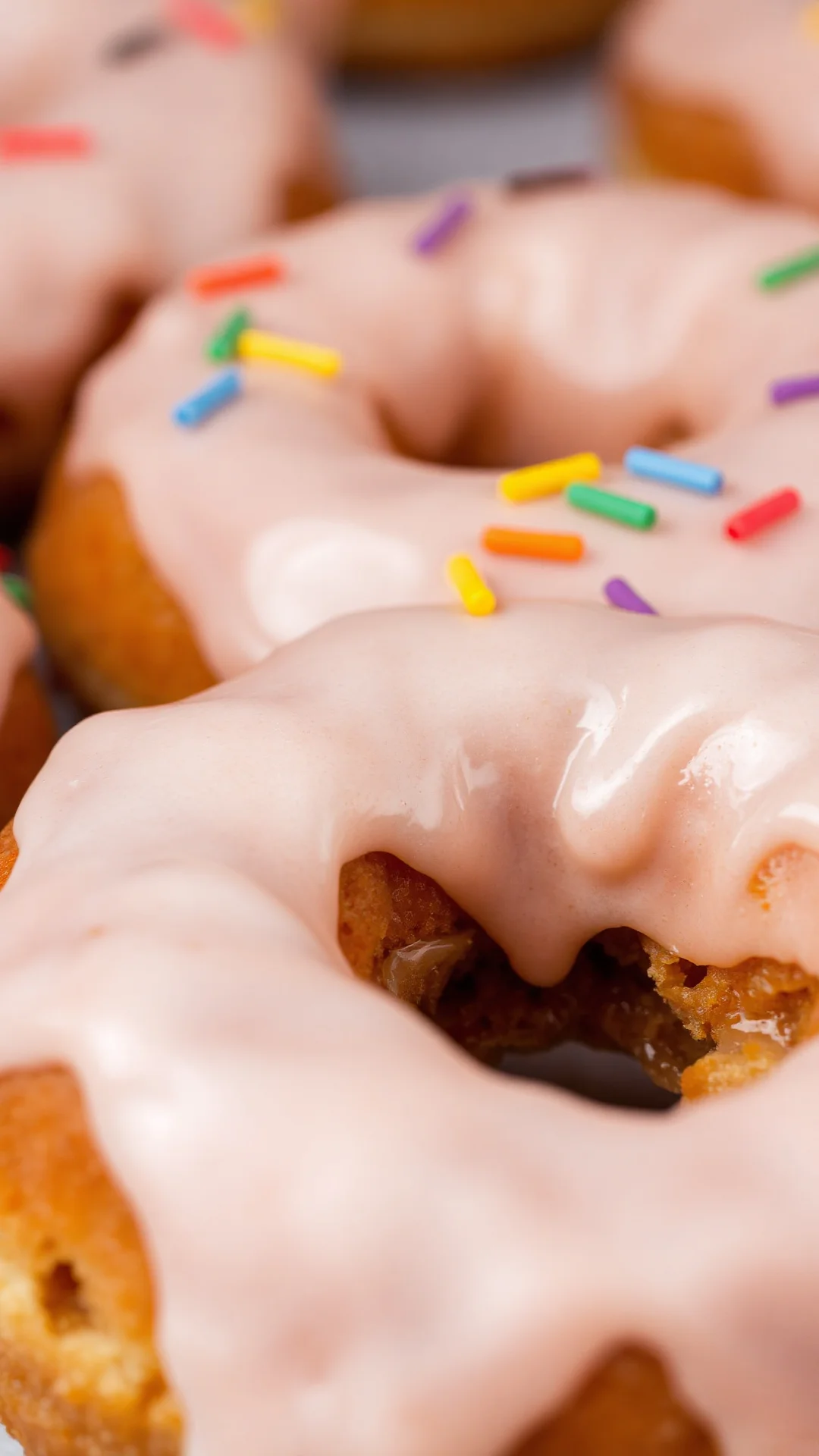 Close-up portrait of a freshly fried donut with glossy white glaze and colorful sugar sprinkles, still warm, professional foo